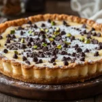 A slice of Cannoli Pie garnished with powdered sugar and pistachios on a rustic table.