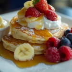 Fluffy coconut banana pancakes cooking on a skillet.