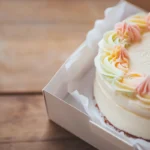 Minimalist bento cake with pastel frosting in a takeout box.